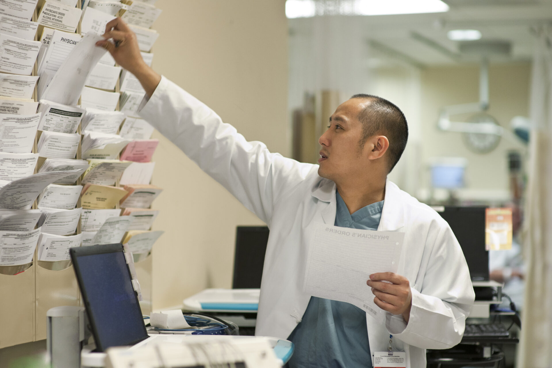 Doctor reaching for a patient's chart in a hospital.