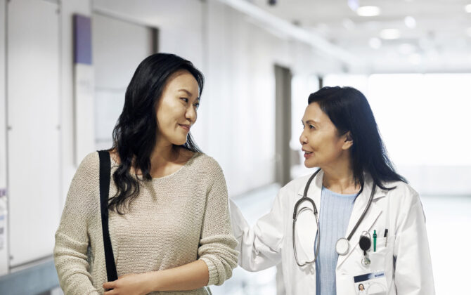 Smiling mature doctor talking to woman in hospital